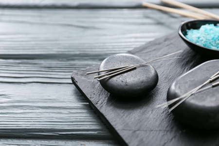 Acupuncture needles and spa stones on tableの写真素材
