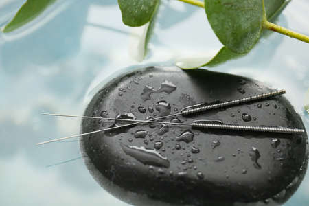 Acupuncture needles and spa stone on waterの写真素材
