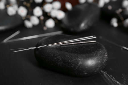 Acupuncture needles and spa stone on dark backgroundの写真素材