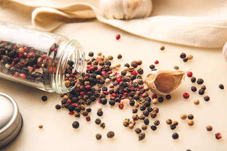 Overturned jar with mixed peppercorns on light backgroundの写真素材