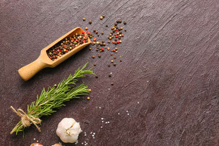 Scoop with mixed peppercorns and rosemary on dark backgroundの写真素材