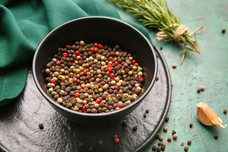 Bowl with mixed peppercorns on color backgroundの写真素材