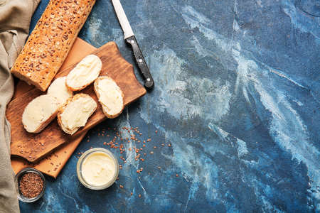 Slices of fresh bread with butter on color background