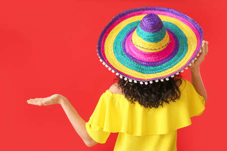 Woman in sombrero hat showing something on color backgroundの写真素材
