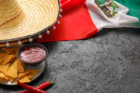 Mexican flag, sombrero hat, chili peppers, nachos and sauce on dark background, closeupの写真素材