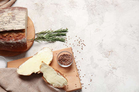 Slices of fresh bread with butter, flax seeds and rosemary on light background