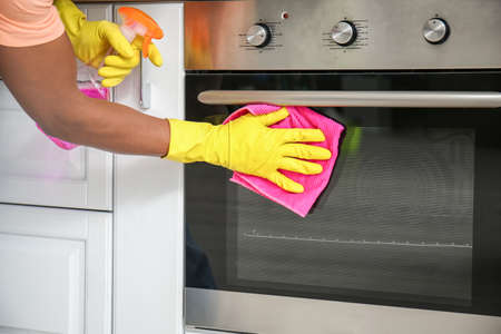 African-American man cleaning oven in kitchenの写真素材