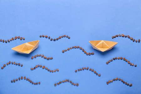 Creative composition with paper boats and coffee beans on color backgroundの写真素材