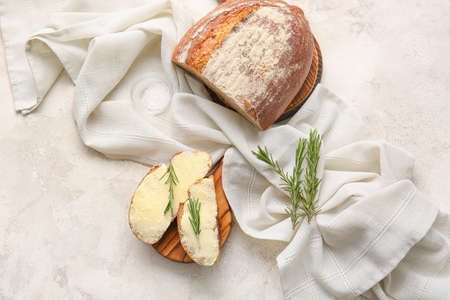 Slices of fresh bread with butter and rosemary on light backgroundの写真素材