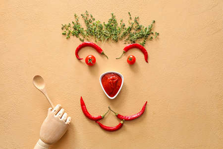 Creative composition with tasty chili sauce, ingredients and wooden hand on color backgroundの写真素材