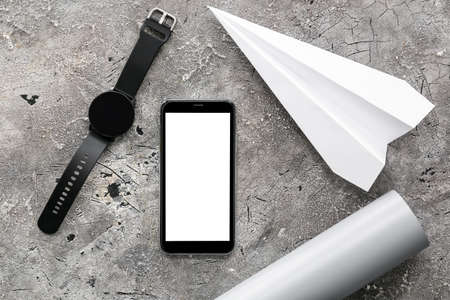 Mobile phone, wrist watch and paper airplane on grunge background