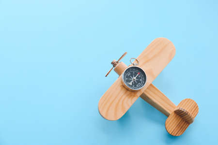 Wooden airplane and compass on color backgroundの写真素材