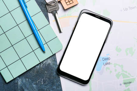 Mobile phone, notebook, map, key and pen on color background, closeup