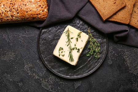 Fresh butter, herbs and bread on dark backgroundの写真素材