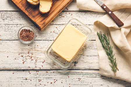 Composition with fresh butter and bread on light wooden background