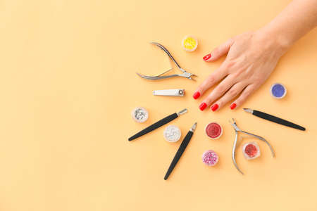 Female hand and tools for manicure on orange backgroundの写真素材