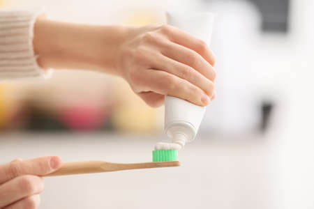 Female hands with tooth brush and paste on blurred backgroundの写真素材