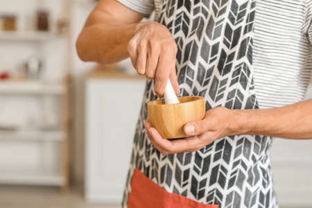 Young man with mortar and pestle in kitchen