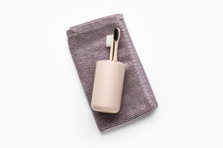 Holder with tooth brushes and towel on white background