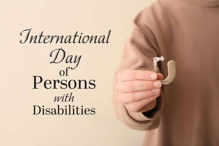 Woman with hearing aid on light background, closeup. International Day of Persons with Disabilitiesの写真素材