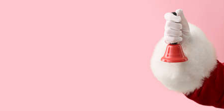Santa Claus holding Christmas bell on color background with space for textの写真素材