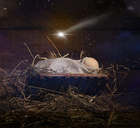 Manger with dummy of baby on dark wooden background. Concept of Christmas storyの写真素材