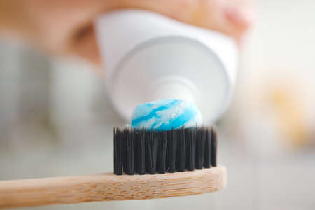 Squeezing of paste onto tooth brush on blurred background, closeup
