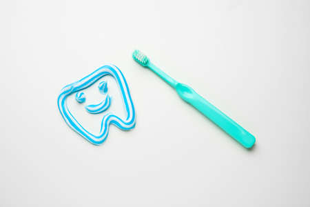 Toothbrush and tooth made of paste on white background