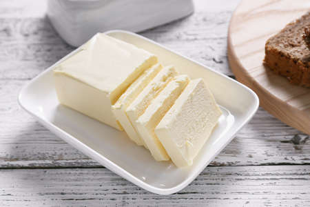 Plate with fresh butter on wooden table