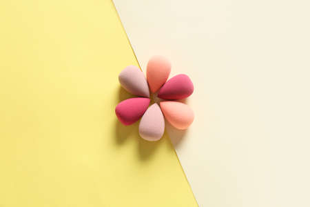 Flower made of makeup sponges on color background