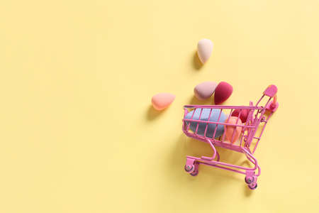 Shopping cart with makeup sponges on color backgroundの写真素材