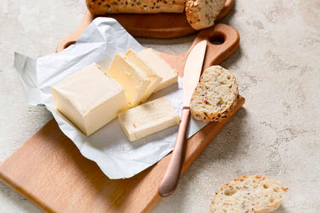 Chopping board with fresh butter and tasty bread on table