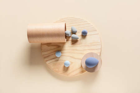Board with makeup sponges on light background