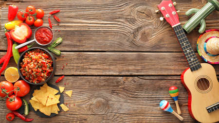 Bowls of tasty salsa sauces with symbols of Mexico on wooden background
