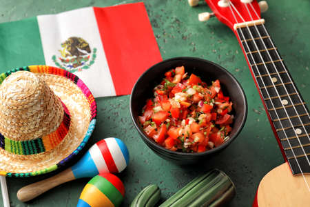 Bowl of tasty salsa sauce with symbols of Mexico on color backgroundの写真素材