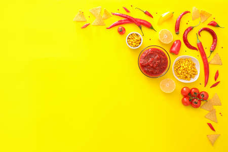 Bowl of tasty salsa sauce with products on color background