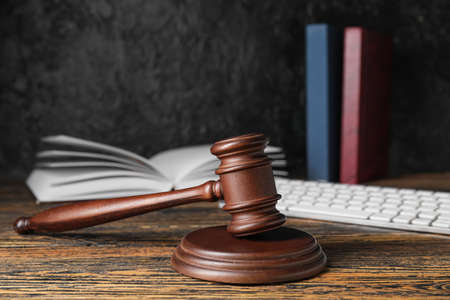 Judge's gavel and law book on dark wooden background