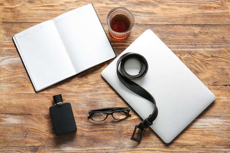 Stylish male accessories, laptop and glass of whiskey on wooden backgroundの写真素材