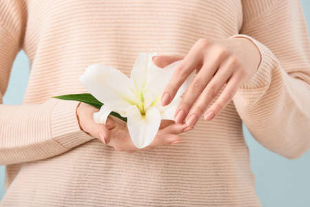 Woman with beautiful manicure holding flower on color background, closeupの写真素材