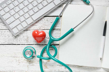 Composition with stethoscope, notebook and computer keyboard on white wooden backgroundの写真素材