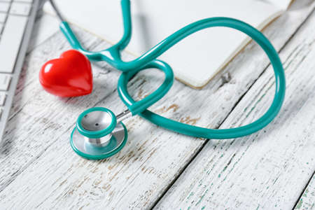 Modern stethoscope and heart on light wooden background, closeupの写真素材