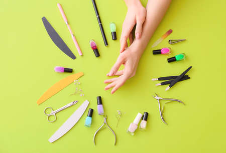 Female hands and professional tools for manicure on color backgroundの写真素材