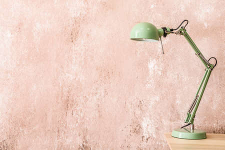Modern lamp on table near color wallの写真素材
