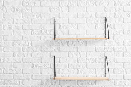 Empty shelves hanging on brick wallの写真素材