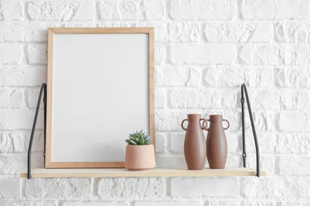 Shelf with frame and decor hanging on brick wall