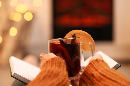Woman with tasty mulled wine near fireplaceの写真素材