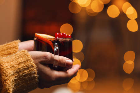 Woman with tasty mulled wine near fireplaceの写真素材