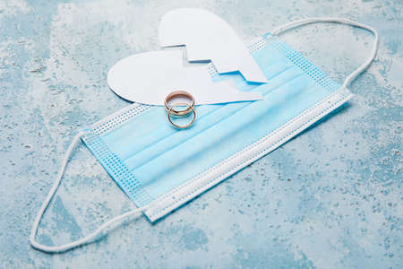 Broken heart with rings and mask on color background