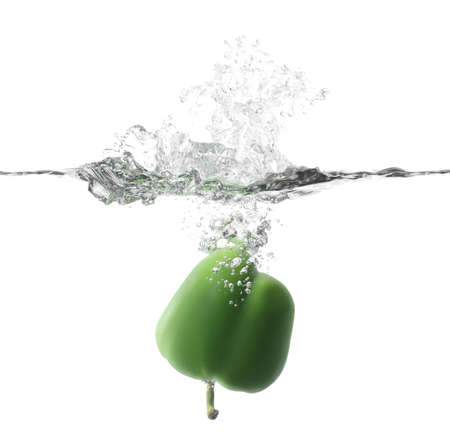 Falling of fresh bell pepper into water against white backgroundの写真素材