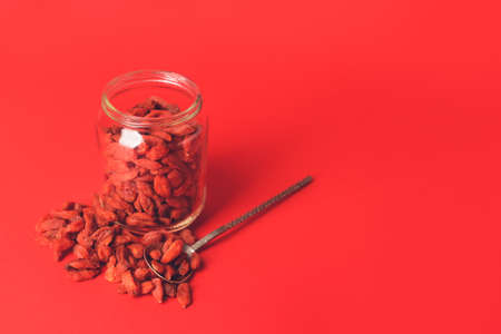 Jar and spoon with dried goji berries on color backgroundの写真素材